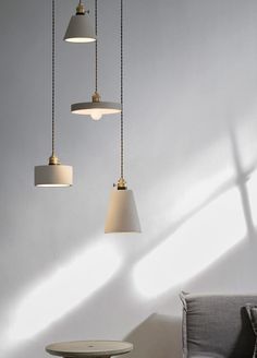 three pendant lights hanging from the ceiling over a table and chair in a living room