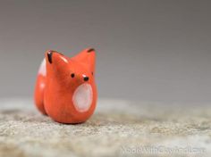 a small orange toy animal sitting on top of a floor next to a gray wall