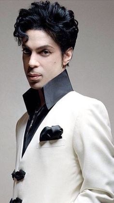 a man with black hair wearing a white suit