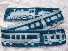 two blue and white knitted headbands with buses on them sitting on a bed