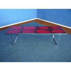 a glass table with metal legs on carpeted flooring and blue walls in the background