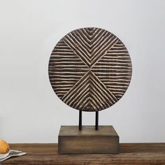 a wooden sculpture sitting on top of a table next to an orange and some other items