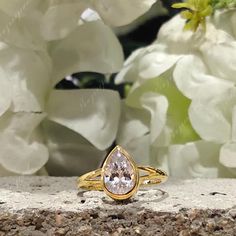 a yellow gold ring with a pear shaped diamond in the center surrounded by white flowers