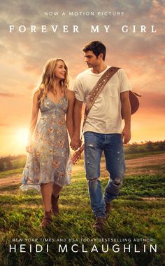 a man and woman holding hands while walking through the grass with sunset behind them in the background