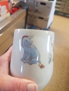 a hand holding a cup with an elephant on it