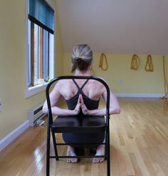 a woman sitting in a chair with her back turned to the camera while doing yoga