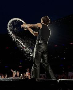 a man standing on top of a stage holding a microphone in front of a crowd