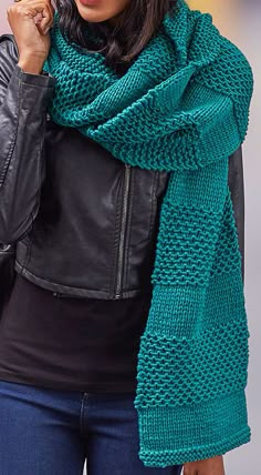 a woman wearing a black leather jacket and green knitted scarf