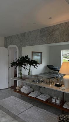 a bathroom with marble counter tops and white towels on the floor next to a plant