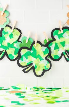 paper shamrocks are hung on clothes pegs to make a garland for st patrick's day