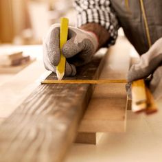 a man working on wood planks with a pair of hands holding a pencil and tape