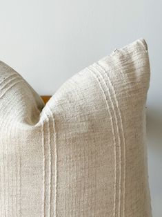 a close up of a white pillow on a wooden headboard in a room with white walls