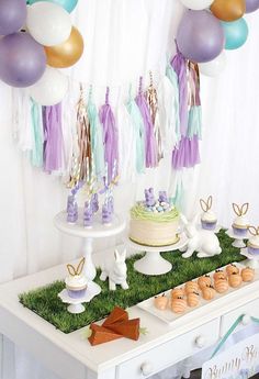 the dessert table is set up with balloons and cupcakes for an easter bunny themed party