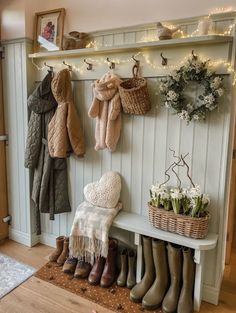 a coat rack filled with coats and boots next to a bench in front of a door