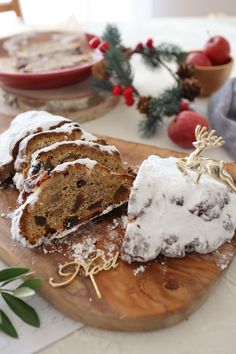 a wooden cutting board topped with slices of cake covered in icing and powdered sugar