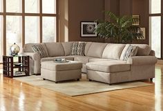 a living room scene with focus on the sectional sofa and footstool in the center