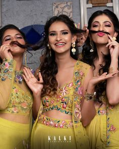 three beautiful women in yellow outfits posing for the camera with fake mustaches on their mouths