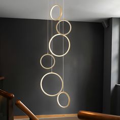 a modern chandelier hanging from the ceiling in a room with black walls and wooden stairs