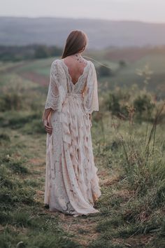 the back of a woman's dress as she stands in a field at sunset