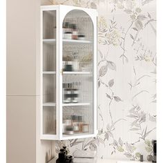 a white cabinet in the corner of a bathroom with floral wallpaper on the walls