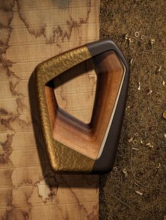 a wood and metal object sitting on top of a wooden table next to some dirt