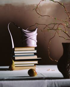 a stack of books sitting next to a vase filled with fruit