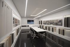 an office with white walls and black flooring, along with rows of bookshelves