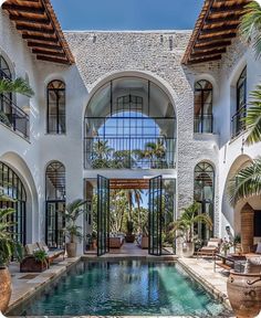 an outdoor swimming pool in front of a large white building with arched windows and doors