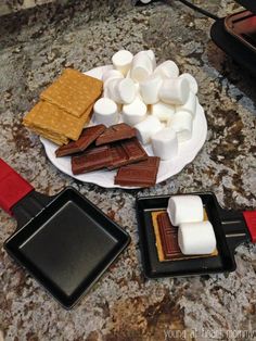 marshmallows and graham crackers are on a plate next to a spatula