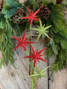 three red and green christmas decorations sitting on top of a wooden table next to pine cones