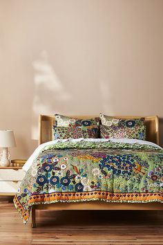 a bedroom with a bed covered in a colorful comforter and matching pillowcases