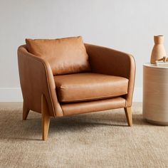 a brown leather chair sitting next to a vase on top of a carpeted floor