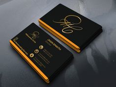 two black and gold business cards on top of a gray surface with the letter g