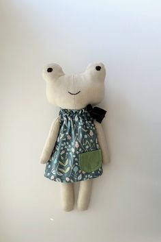 a stuffed animal with a green dress and black bow on it's head hanging from the wall