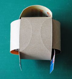 an empty roll of toilet paper sitting on top of a green table next to a cup