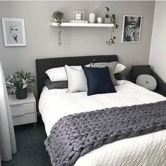 a bed with white sheets and pillows in a bedroom next to pictures on the wall