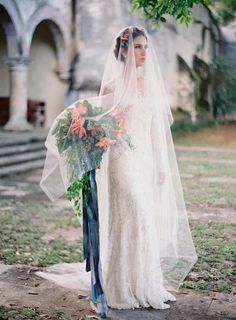 a woman in a wedding dress holding a bridal gown and bouquet with orange flowers