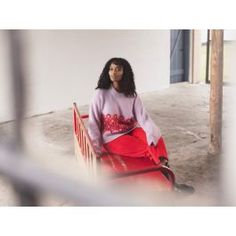 a woman sitting on top of a red bench