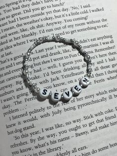 an open book with a bracelet that says seven on it and two beads in the middle