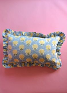 a blue and yellow pillow on a pink background