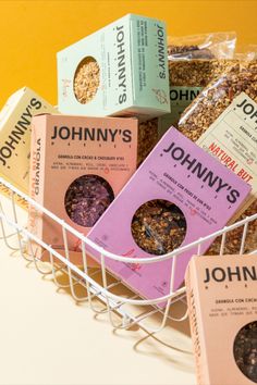 several boxes of johnny's granola sitting in a white basket on a table