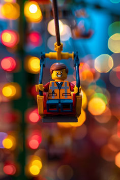 a lego man hanging from a string with lights in the background