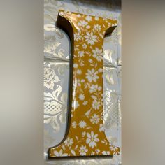 the letter i is made out of yellow and white paper with floral designs on it