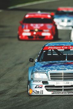 two cars racing on a race track, one is blue and the other is red