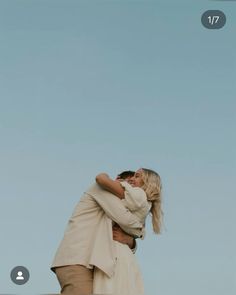 a man and woman embracing each other in front of a blue sky