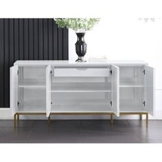 a white sideboard with three doors and two drawers in front of a black wall