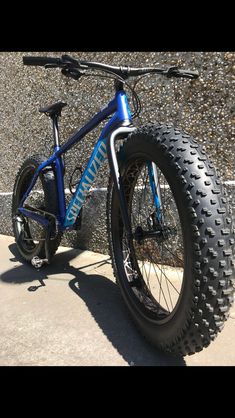 a blue mountain bike parked next to a stone wall