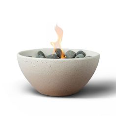 a white bowl filled with rocks on top of a white table next to a fire pit