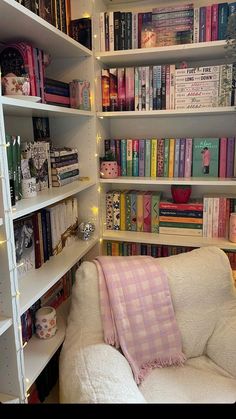 a white couch sitting in front of a book shelf filled with books