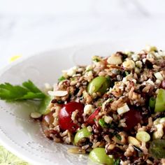 a white plate topped with a salad covered in lots of veggies and nuts